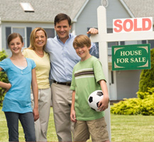 Family standing next to Sold sign